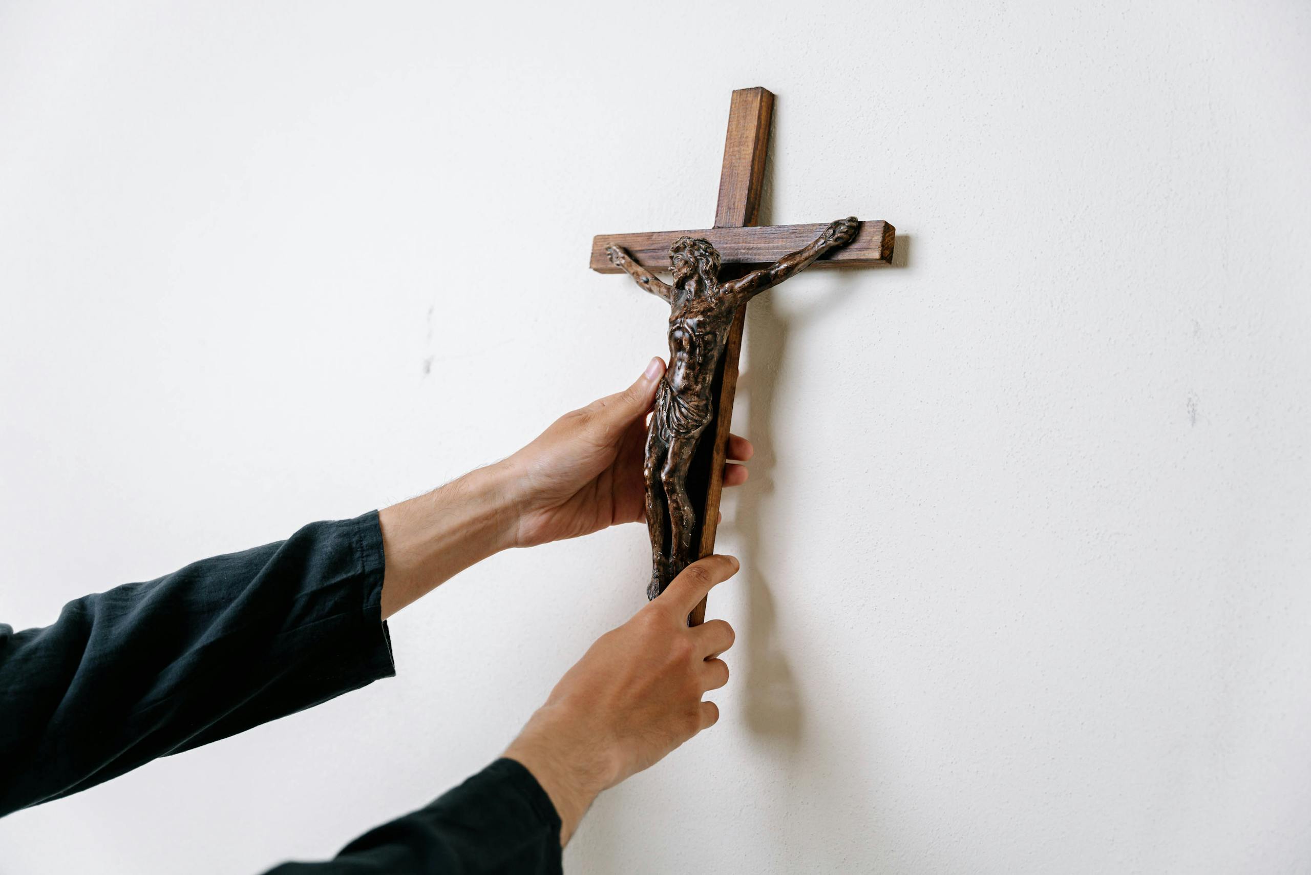 A Person Holding a Wooden Cross on a Wall